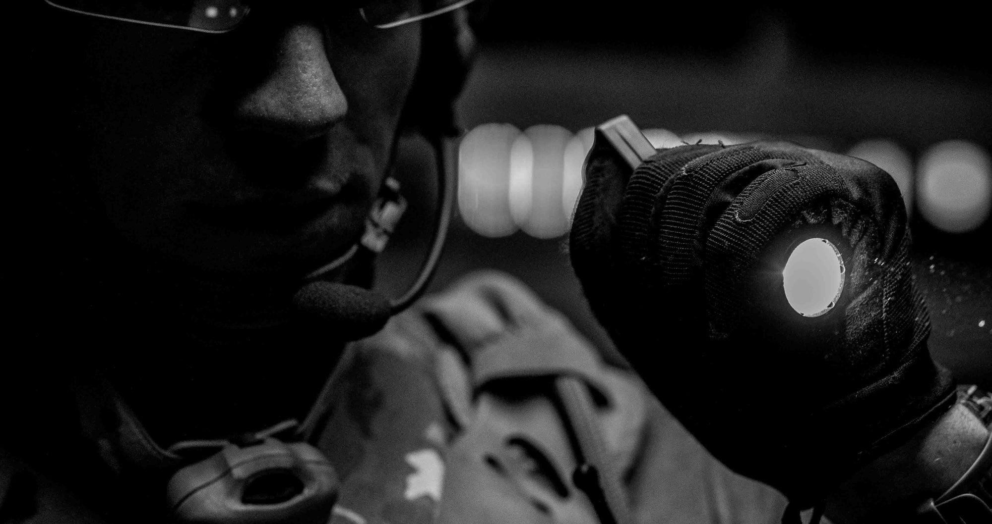 Person wearing a helmet and gloves with a flashlight with a Thyrm Switchback attached to it.