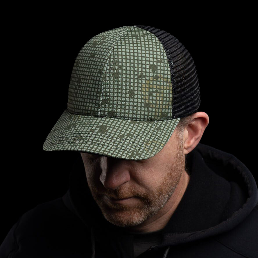 Man wearing Thyrm camouflage trucker hat featuring a custom DNC patterned front and black mesh back.