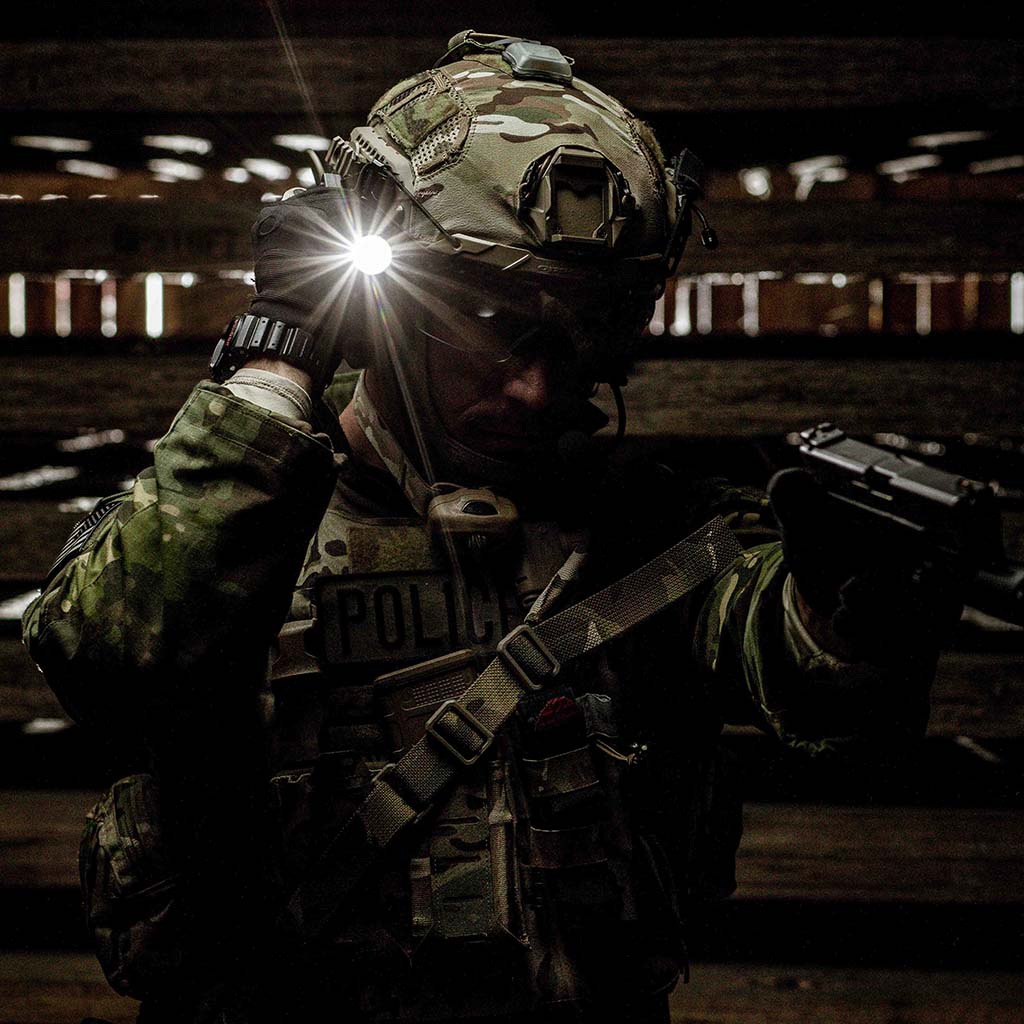 Person in tactical gear with a SwitchBack-mounted flashlight in a dark setting