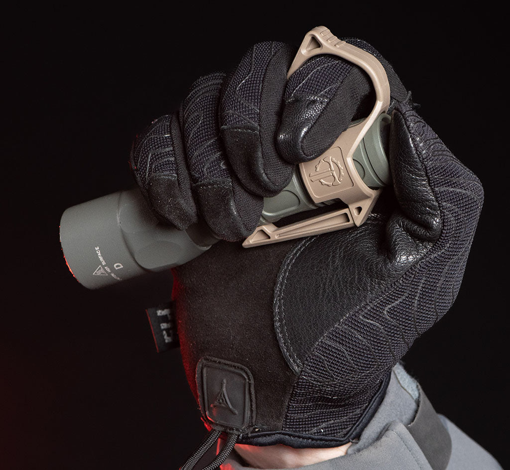 Gloved hand gripping a flashlight with a Thyrm SwitchBack on it
