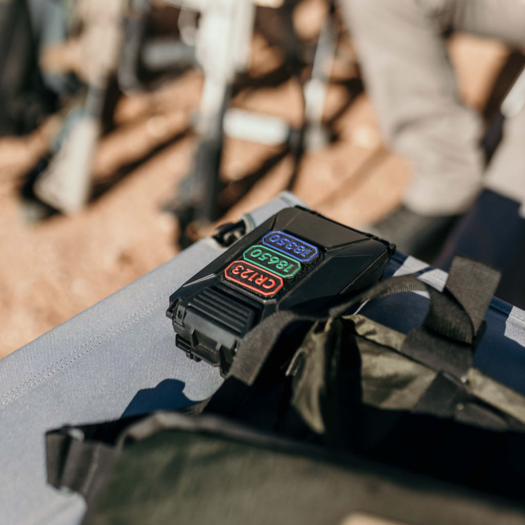 Thyrm CellVault-5M next to a bag with blurred people and chairs in the background