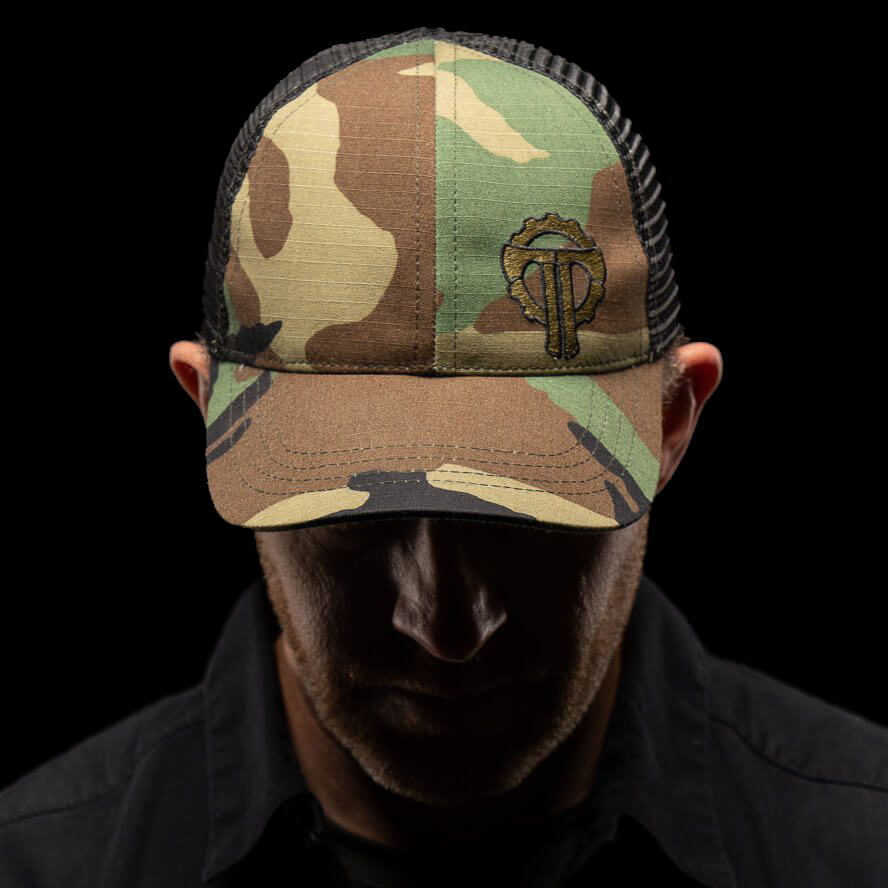 Thyrm Camouflage cap with a logo worn by a person against a black background