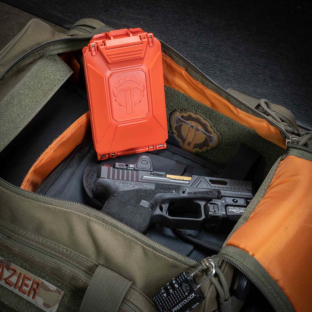 Rescue Orange CellVault-5M Battery Case propped up in a range bag.
