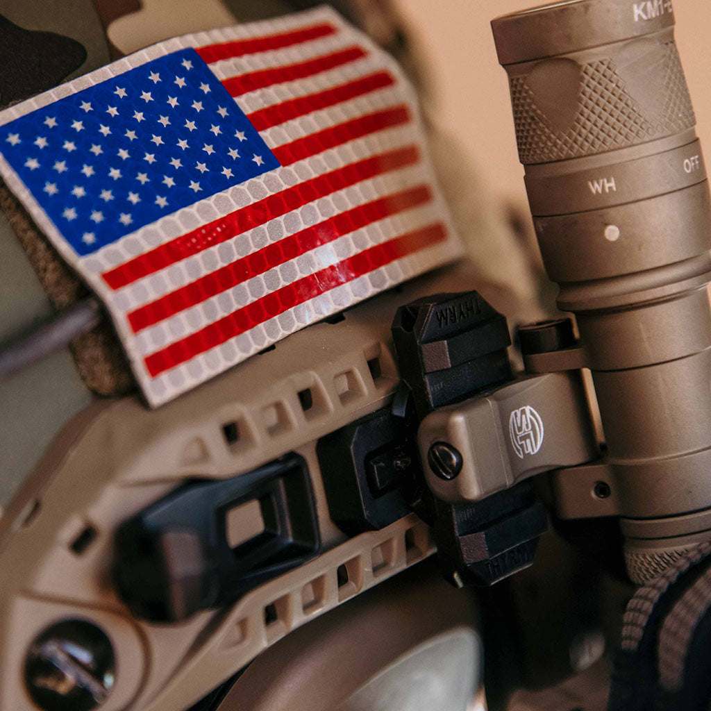 Tactical flashlight mounted with a Thyrm VariArc on a helmet, with an American flag patch