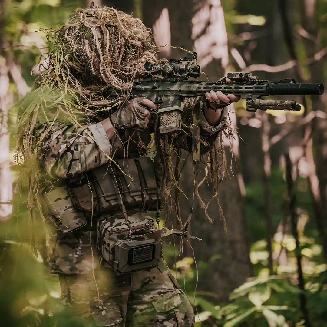 Sniper with camouflage material over the head in the woods