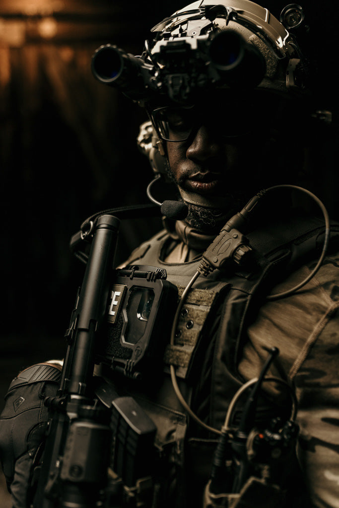 Person in tactical gear, in low light, with a Thyrm VariArc on his helmet and DarkVault Comms 2.0 Critical Gear Case on his chest mount