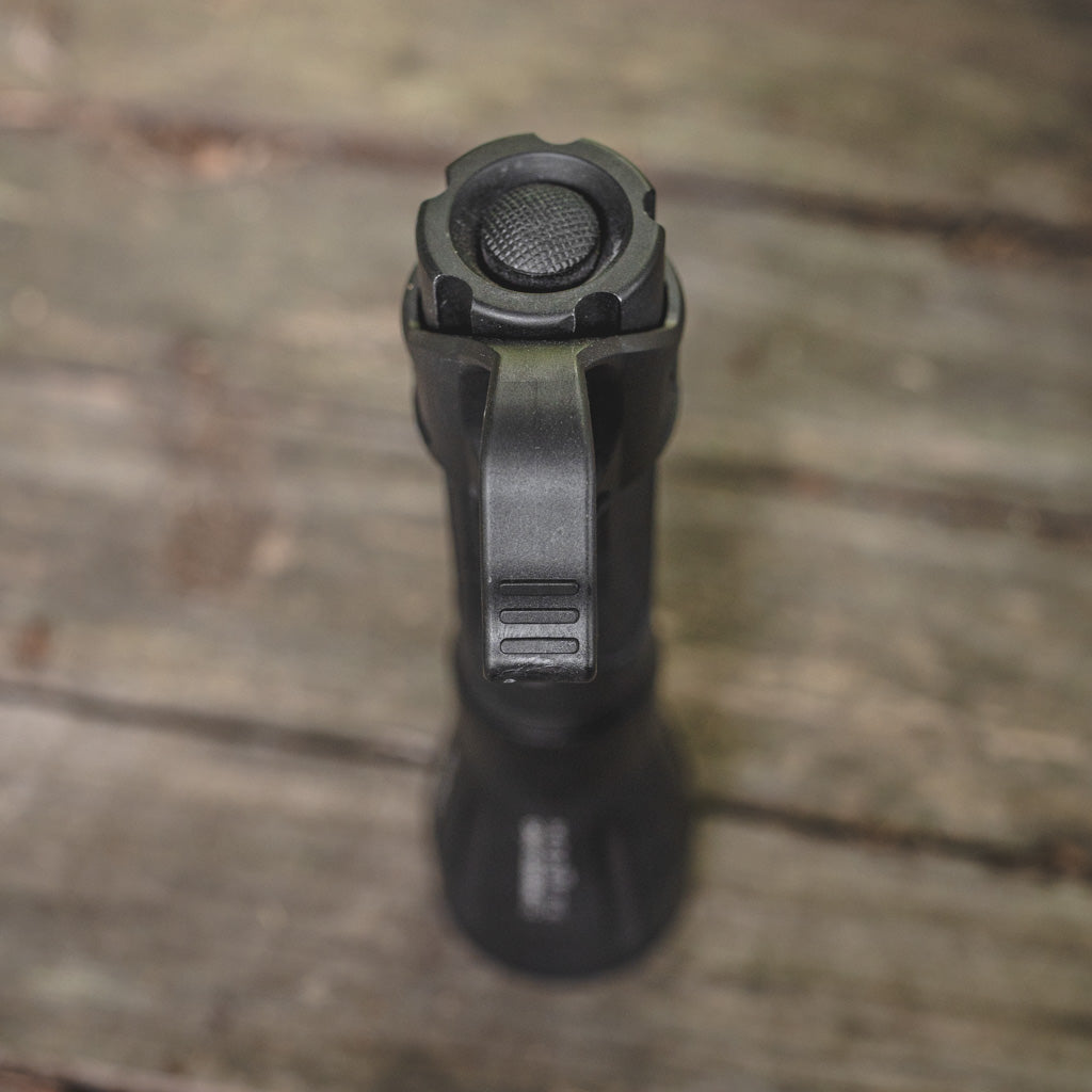 Black Modlite flashlight with a Thyrm SwitchBack on a wooden surface