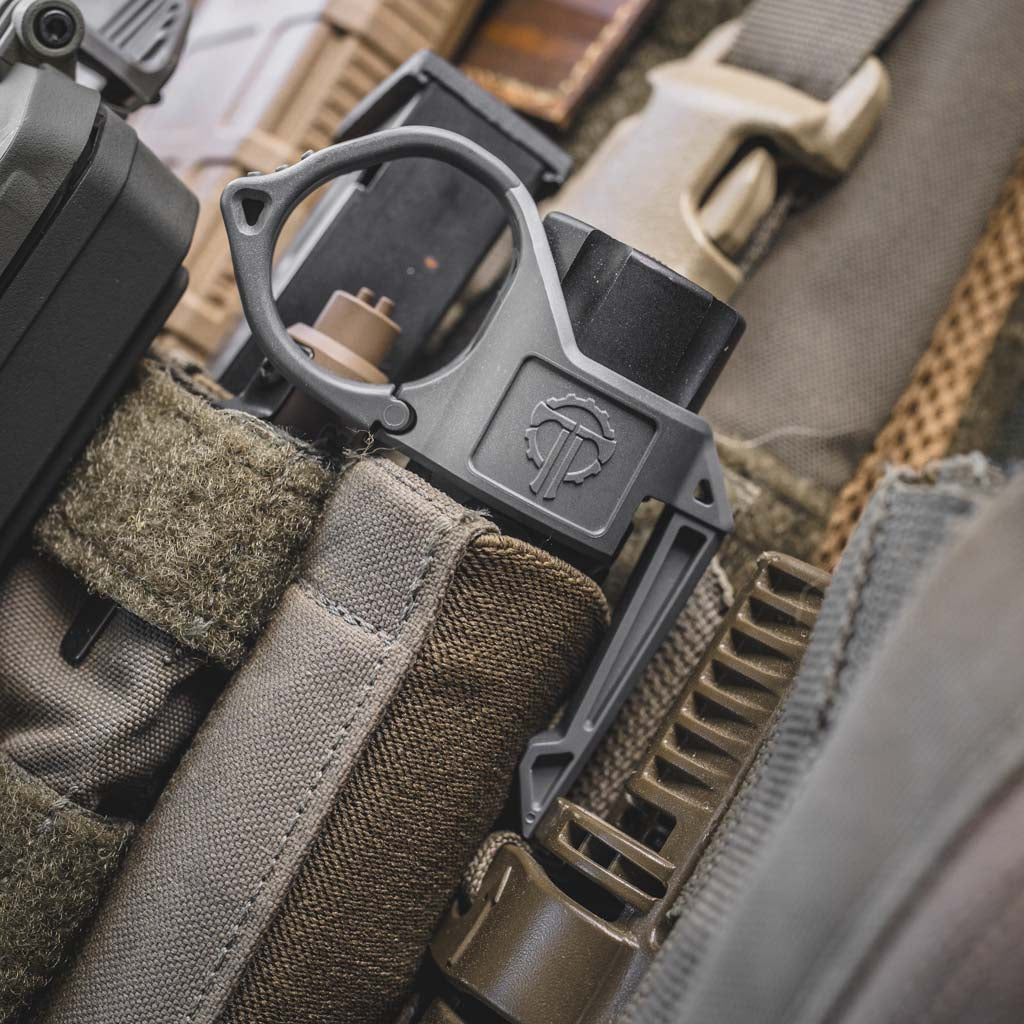 Close-up of tactical gear with a Thyrm SwitchBack Flashlight Ring on a modlite flashlight.