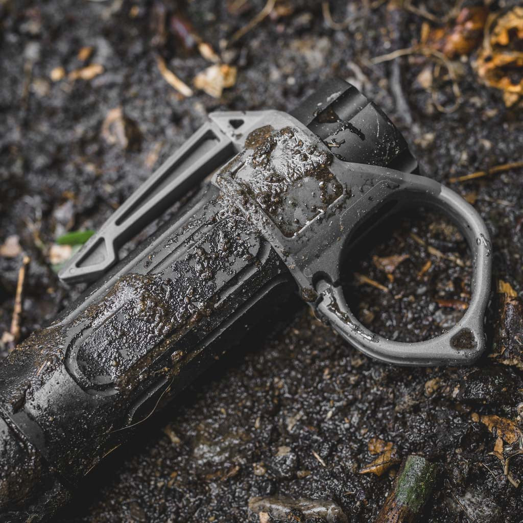 Muddy Modlite flashlight with a Thyrm SwitchBack flashlight ring on a muddy surface