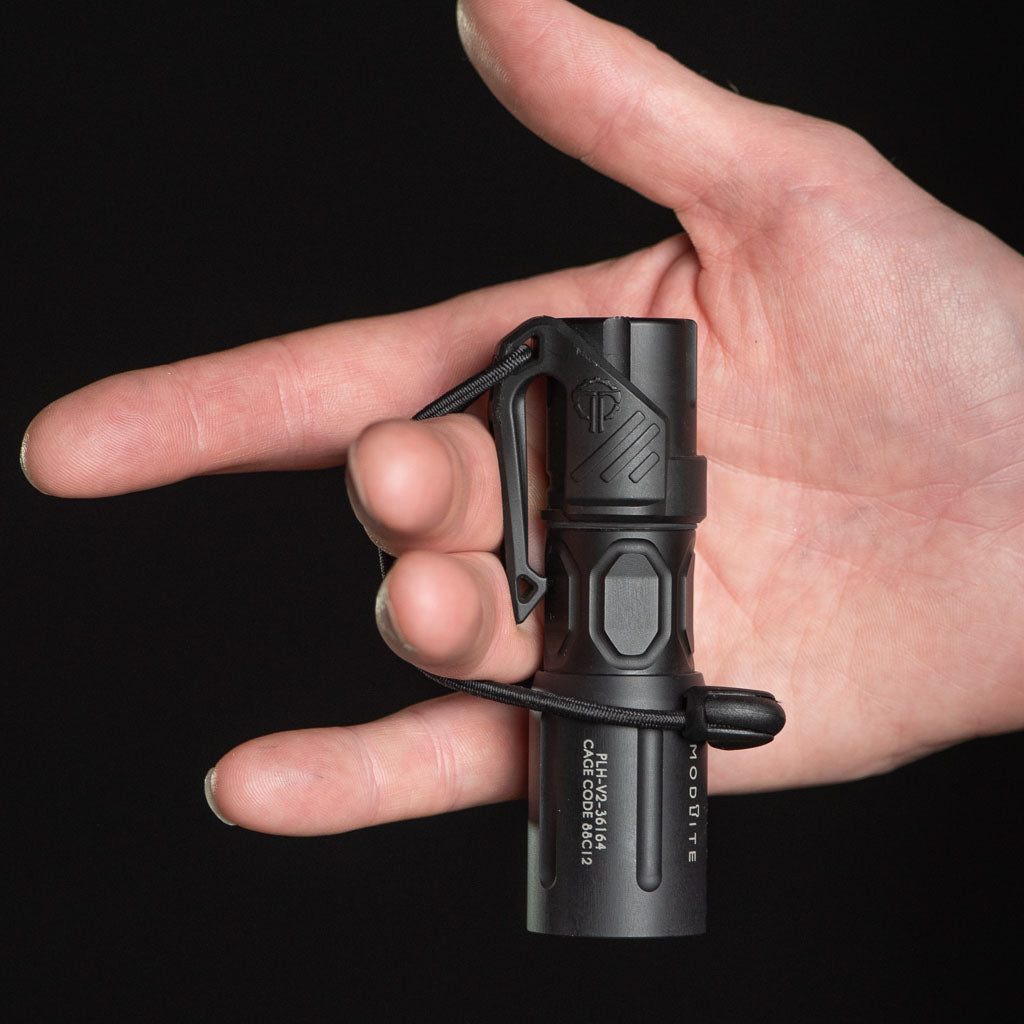 Hand holding a black Modlite flashlight with a Thyrm LPC Clip attached, with a lanyard loop wound around two fingers