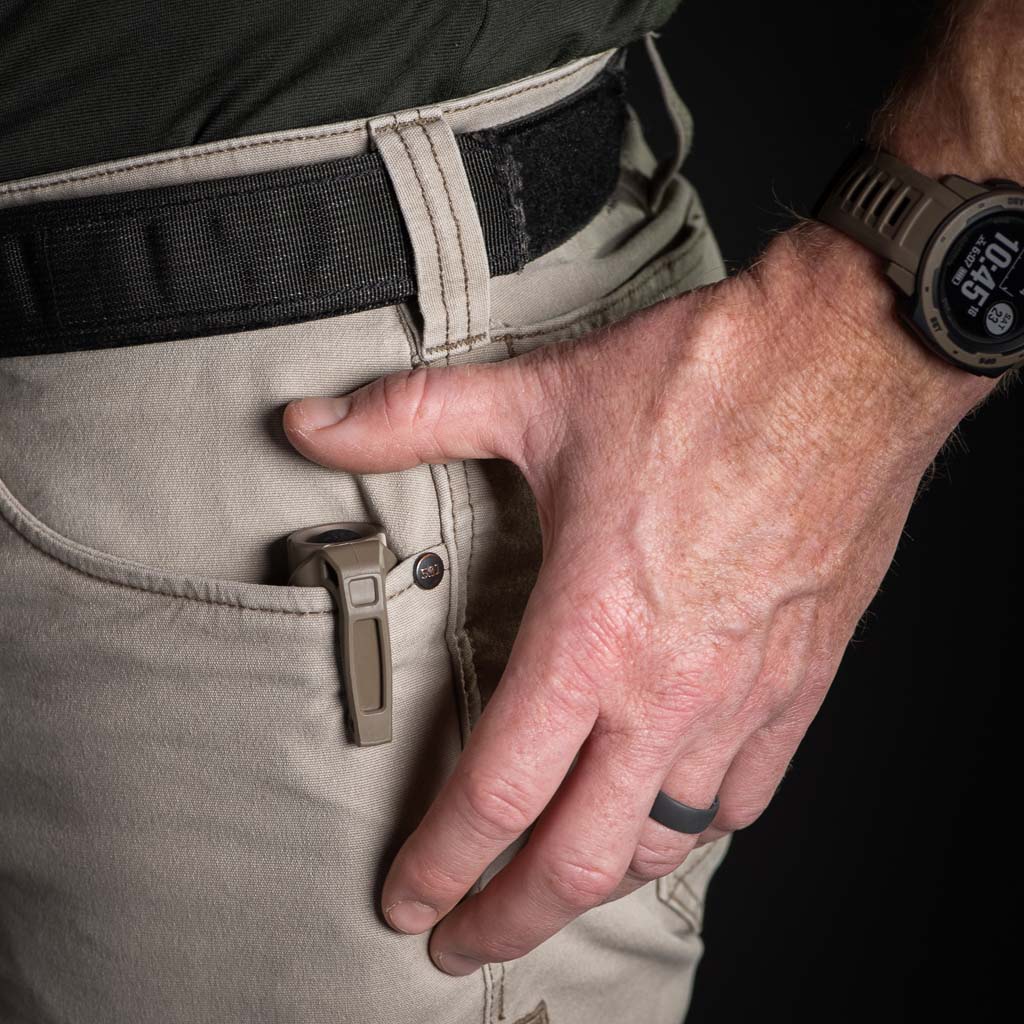 Person wearing beige pants with a pocket and a black belt, hand reaching towards pocket with a Thyrm LPC Clip attached to a flashlight. 