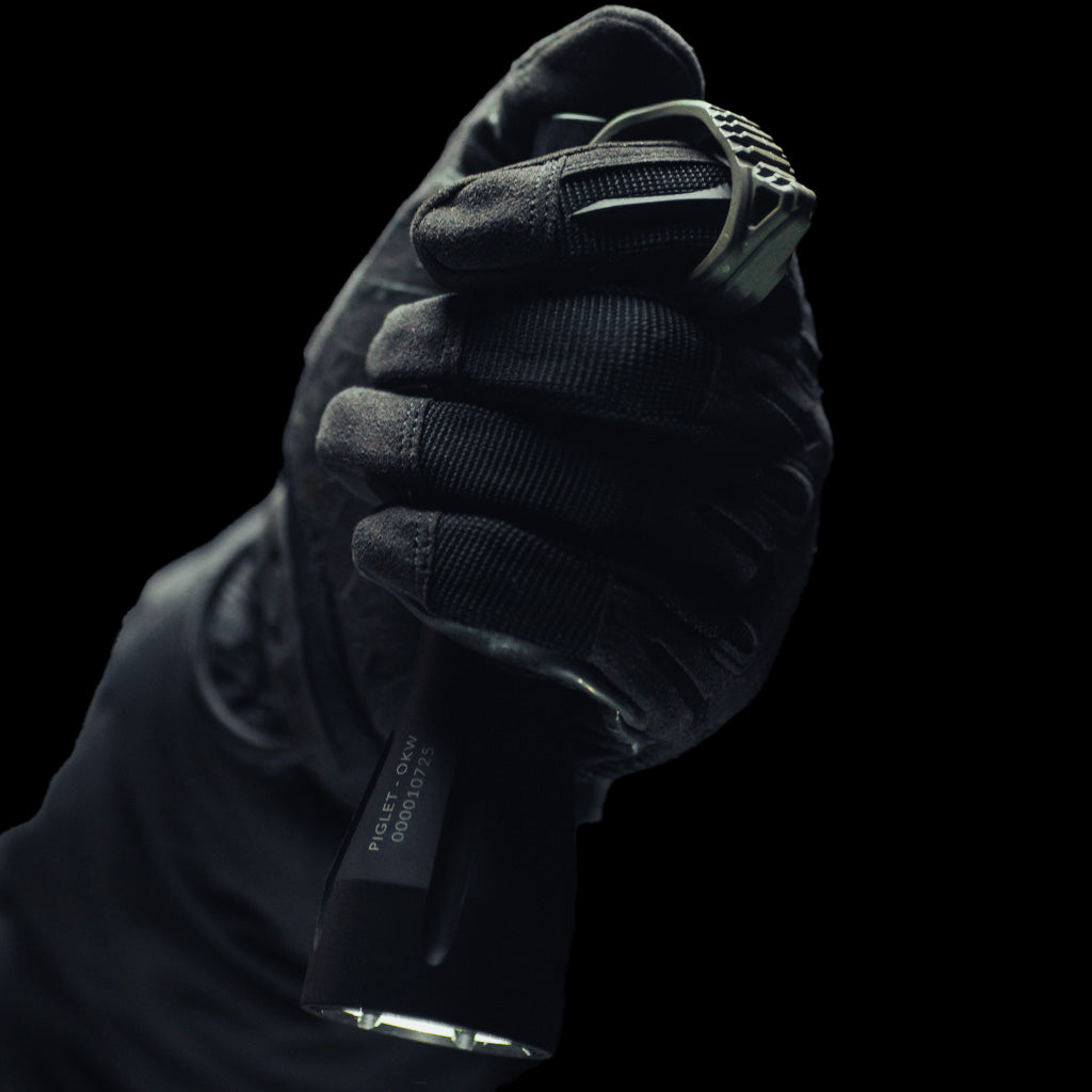 Black tactical glove hand holding a Modlite flashlight with Thyrm Switchback