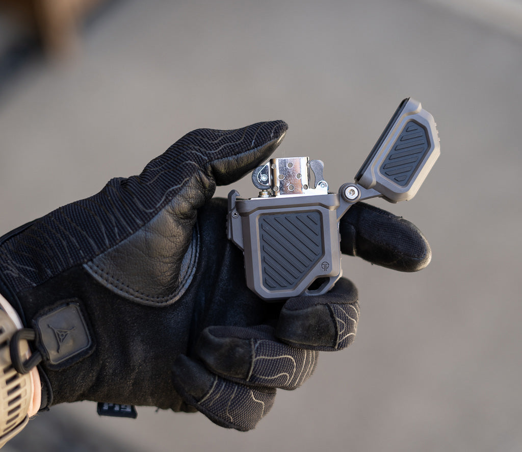 Gloved hand striking the flint wheel of a lighter inside a Thyrm PyroVault 2.0 Case