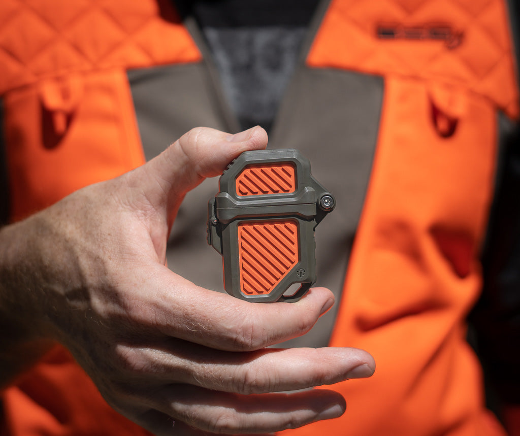 Person in a hunting vest holding one model of hunting orange Thyrm PyroVault 2.0 Lighter Armor