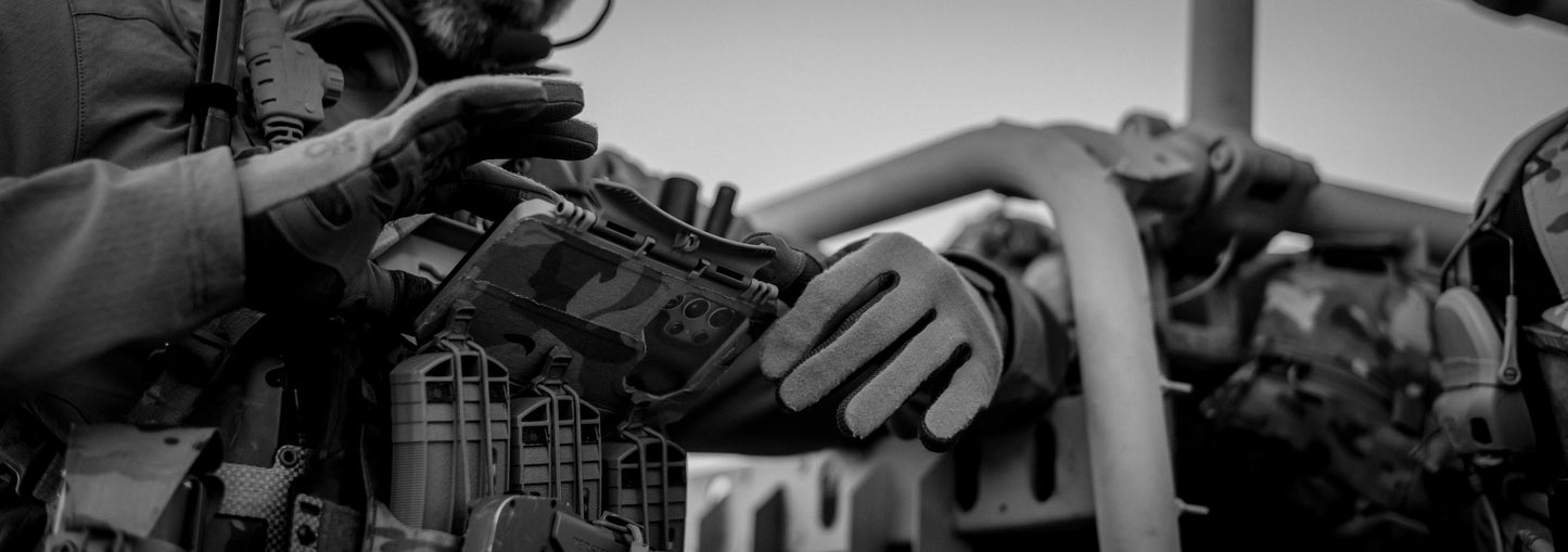 Person in tactical gloves interacting with a smart phone mounted in a Thyrm DarkVault 2.0 Critical Gear Case, size large.