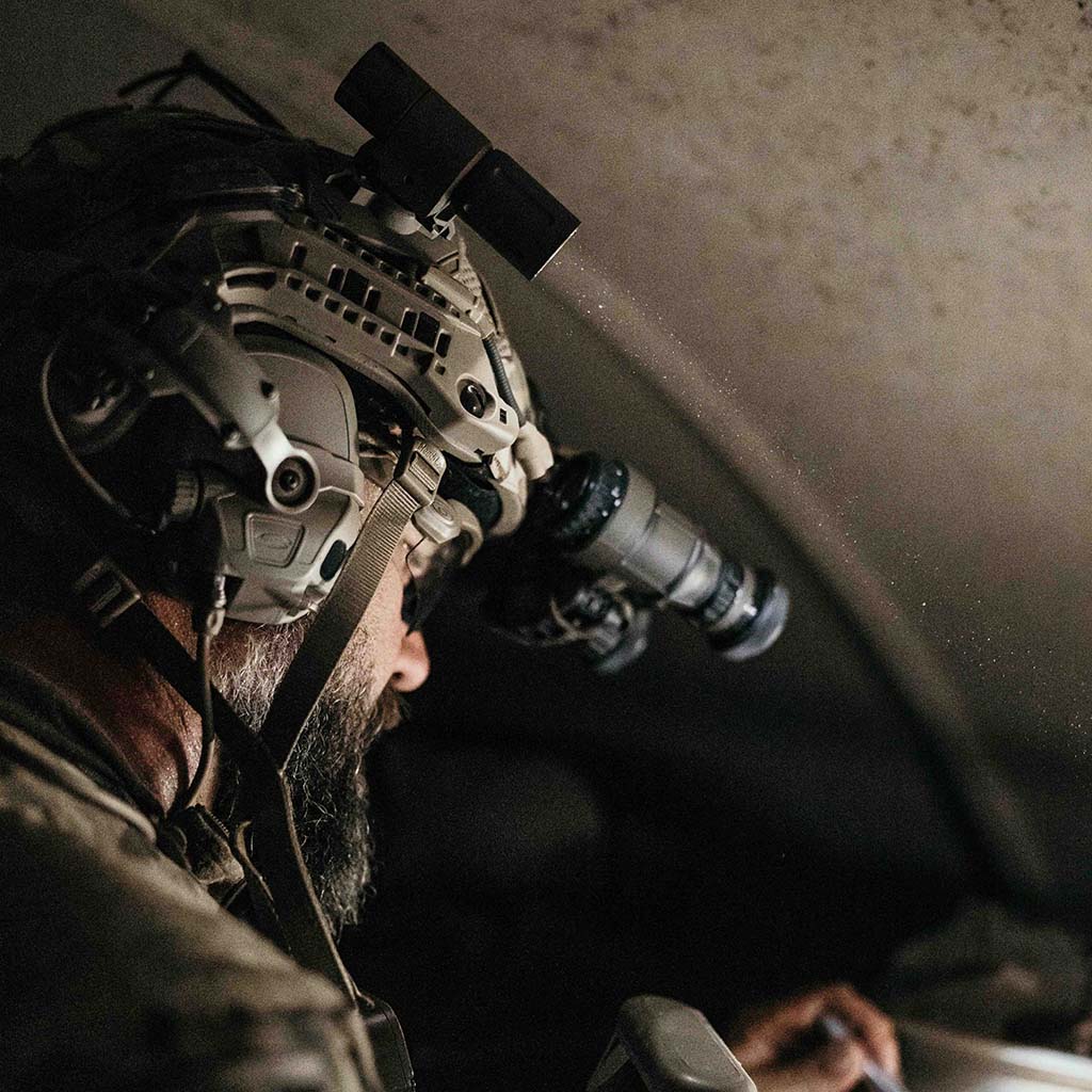 Person wearing a tactical helmet with Thyrm VariArc-mounted light illuminating a dimly lit room.