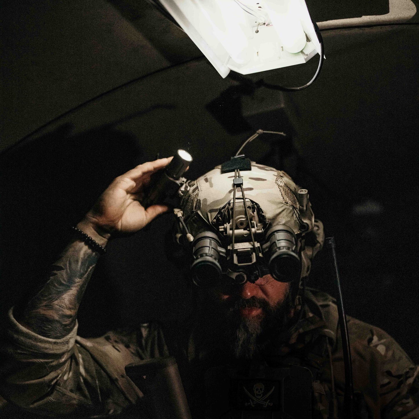 Person wearing a tactical helmet with night vision goggles and a Thyrm VariArc in the dark.