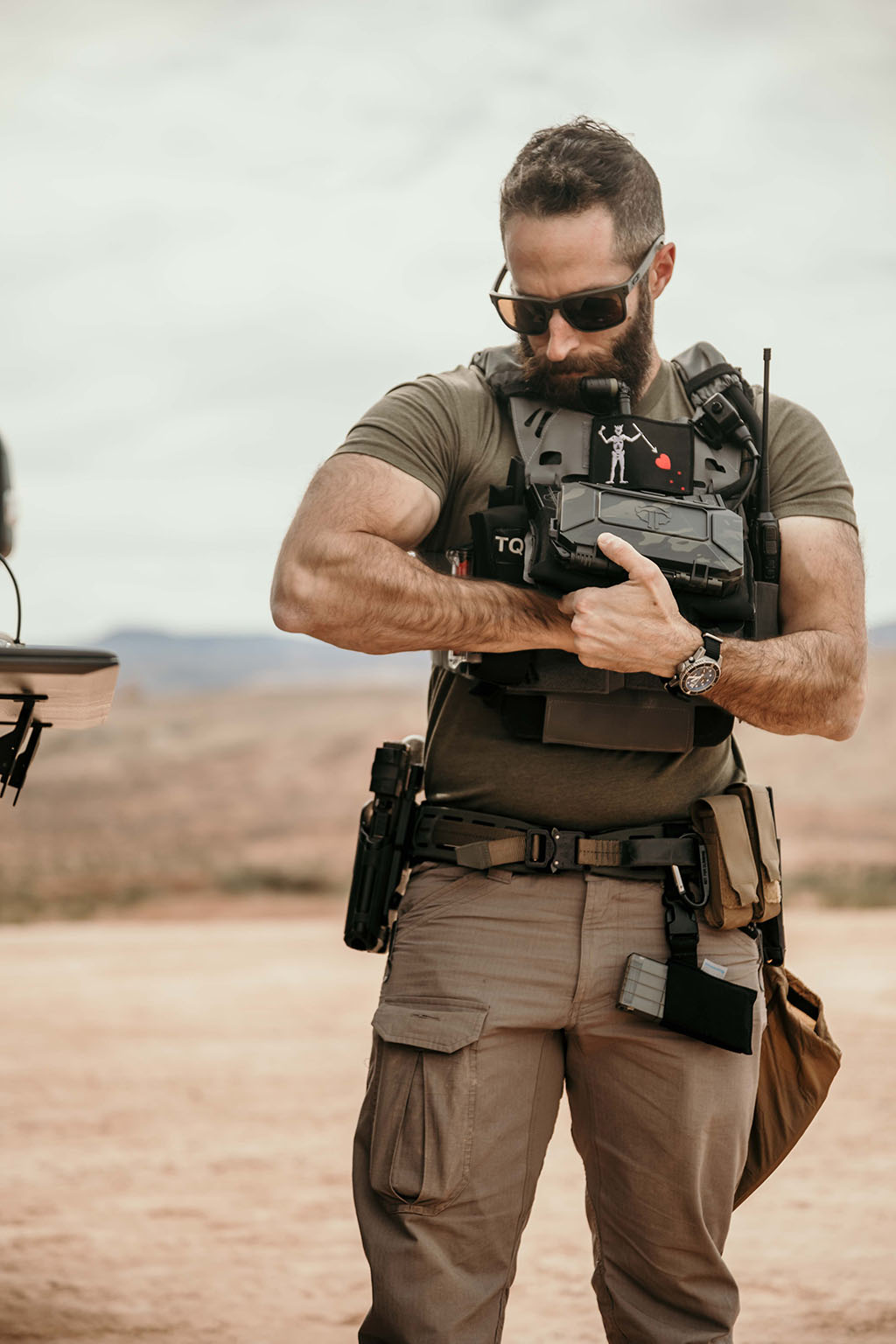 Man adjusting gear at his torso. The DarkVault stays mounted to his chest rig through a movable latching system.