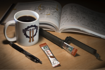 Open CellVault showing its contents: coffee, alongside a book, pen, and cup of joe in a nighttime photo