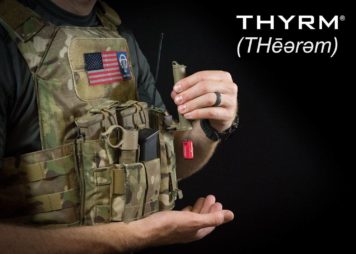 Person wearing chest rig with SwitchBack on light, CellVault inverted with CR-123 coming out, and Thyrm and American Flag patches