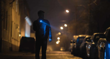 Man illuminating cars with a flashlight on a dark street