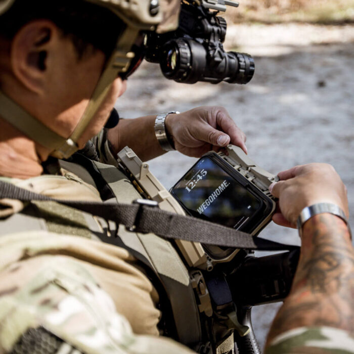 Soldier using WeGoHome on his phone, mounted in a DarkVault Comms 2.0 Critical Gear Case
